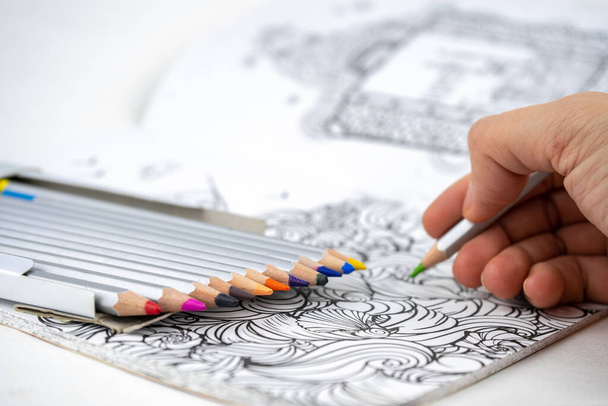Набір кольорових олівців у коробці та розмальовка на столі
 - Фото, зображення