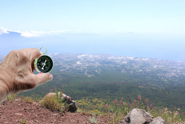 Ręka z klasycznym kompasem na tle letniskowego krajobrazu jako symbol turystyki z kompasem, podróży z kompasem i zajęć na świeżym powietrzu z kompasem - Zdjęcie, obraz