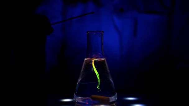 Een laboratoriumwetenschapper mengt verschillende kleurenoplossingen op een magneetroerder UV-licht met de rollende beweging van het mengen in een chemisch laboratorium voor medische chemie - Video