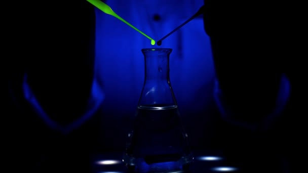 Een wetenschapper mengt een rode en groene kleur oplossing op een magnetische roerder onder blauw licht met de wervelende beweging van het mengen in een chemisch laboratorium voor medische chemie - Video