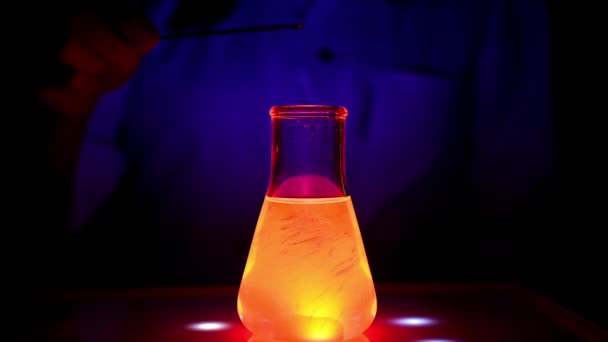 Tiedemies sekoittaa punaisen värin liuoksen magneettisekoittimeen UV-valo ja liikkuvan liikkeen sekoittamalla kemian laboratoriossa lääkekemian - Materiaali, video