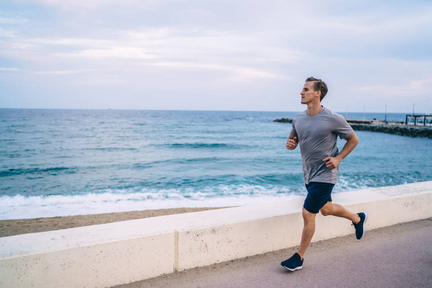 Serious handsome 20s hipster guy jogging in morning on active healthy lifestyle reaching fitness goals, caucasian sportsman running on cardio workout training body and physical body strength - 写真・画像