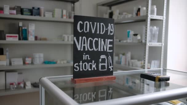 Vacuna COVID-19 en stock inscrita en una pizarra en una farmacia - Imágenes, Vídeo