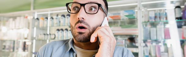 sokkos férfi szemüvegben beszél okostelefonon a gyógyszertárban, banner - Fotó, kép
