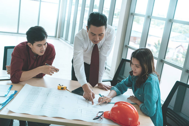 Le patron de la construction avec l'ingénieur et l'architecte discute sur la table de travail avec le plan de construction - Photo, image
