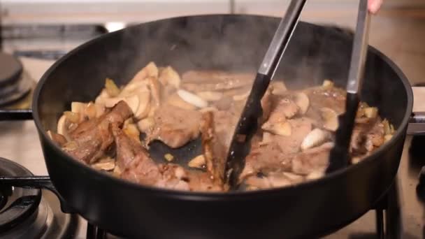 Gebratene Schweinefleischstücke mit Pilzen in der Pfanne, Nahaufnahme. - Filmmaterial, Video