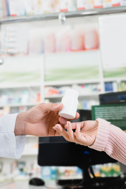 cropped view of pharmacist giving bottle with pills to customer - Foto, Bild