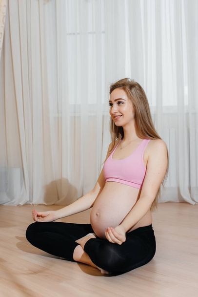 A pregnant girl does yoga at home. Health - Foto, immagini