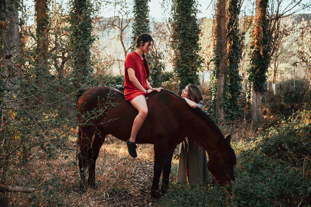 İki kadın arkadaş sohbet ediyor ve atlarıyla kırsalda geziyorlar. - Fotoğraf, Görsel
