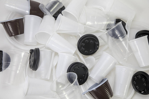 Utensili di plastica usa e getta sparsi sul tavolo, utensili di plastica in un mucchio, tazza, bicchieri, cucchiai e forchette - Foto, immagini
