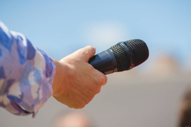 De journalist houdt een microfoon in zijn hand tijdens een interview - Foto, afbeelding