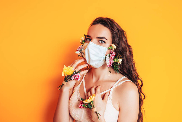 Nuori nainen yllään lääketieteellinen naamio valmistettu kukista pandemian aikana. - Valokuva, kuva