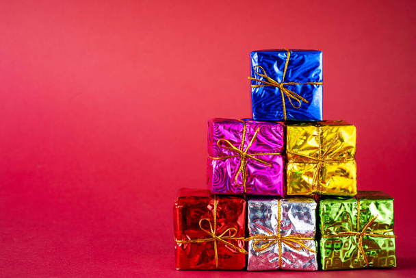 Multicolored bright holiday gift boxes  on a red background. Copy space. - Foto, imagen