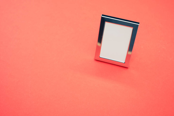 Eine Hochwinkelaufnahme eines kleinen einfachen Fotorahmens isoliert auf orangefarbenem Hintergrund - Foto, Bild