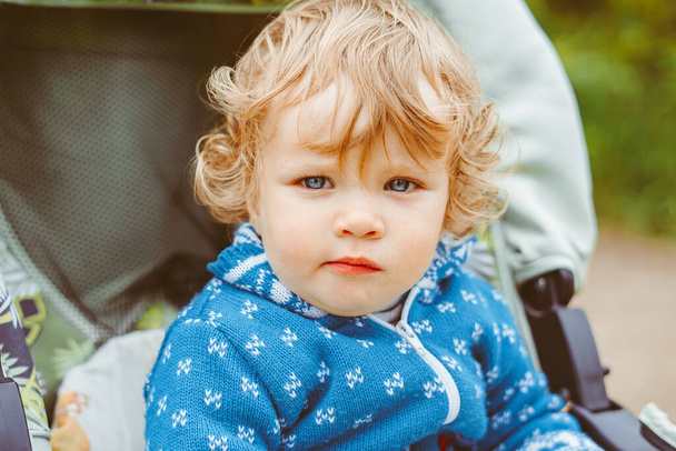 kis boldog fiú ül egy babakocsiban egy kék blúzban - Fotó, kép