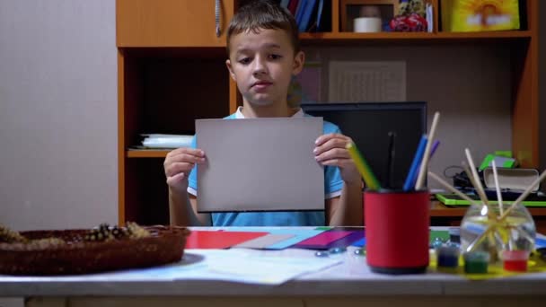Mavi Tişörtlü Ciddi Çocuk Renkli Kağıt 'ta Gri Elleri Gösteriyor - Video, Çekim
