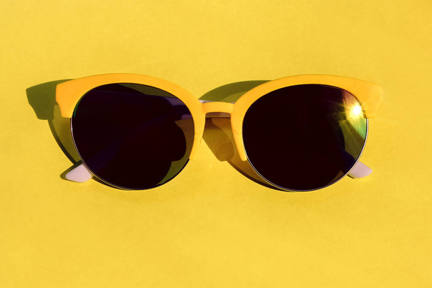 Sarı arka planda sarı çerçeveli güneş gözlüğü. Yetişkinler ve çocuklar için eğlenceli yaz aksesuarları - Fotoğraf, Görsel