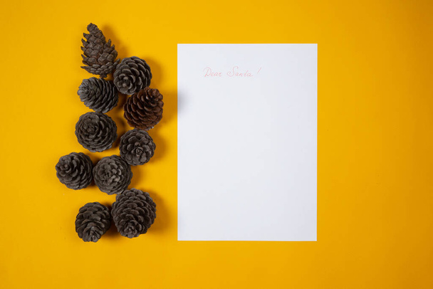 Carta de los niños a Santa para Navidad sobre fondo amarillo con conos de pino - Foto, imagen