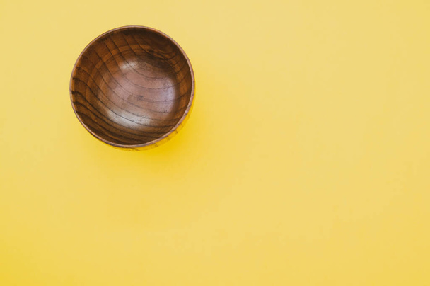A top view of a wooden bowl on yellow background - Fotoğraf, Görsel