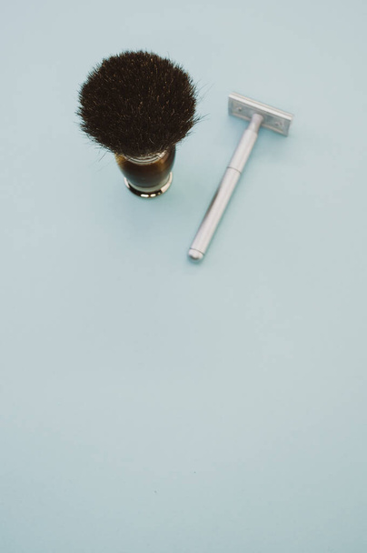 A vertical shot of a shaving brush and a blade on pastel gray background - Foto, immagini