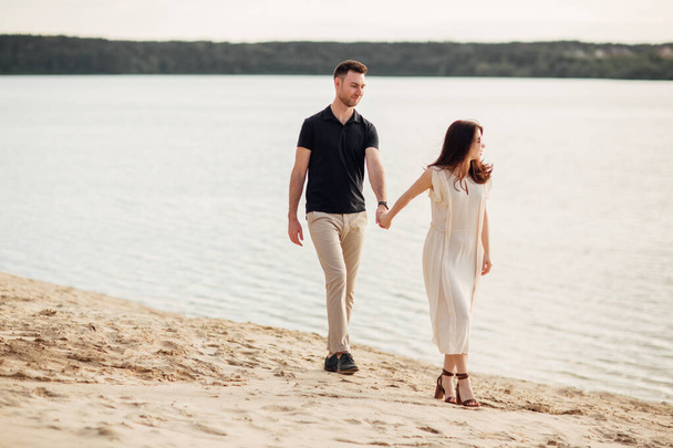 elegancka i stylowa kobieta i zakochany mężczyzna spacerują wzdłuż jeziora. Szczęśliwe chwile razem. historia miłosna. - Zdjęcie, obraz