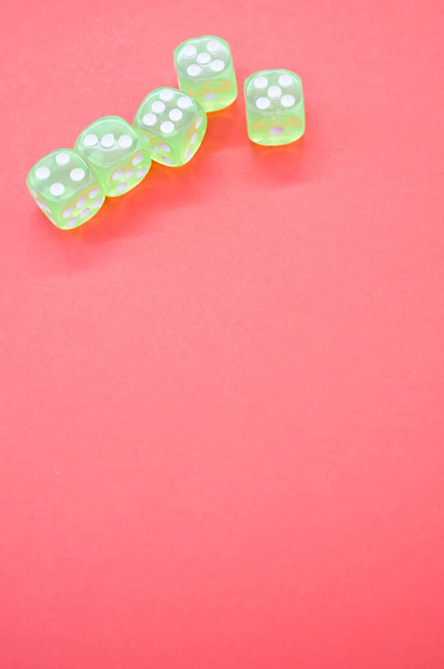 A top view closeup of five neon green dice isolated on a bright pink background - Foto, Bild