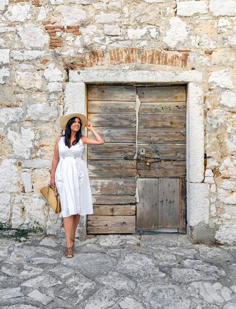 a vertical shot of a white Caucasian woman posing in the countryside road next to a wooden door - Foto, immagini