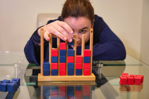 Young woman playing the board game connect four with red and blue pieces - Photo, Image