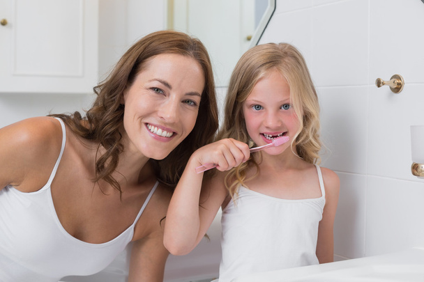 Portrait of mother with daughter brushing teeth - Фото, зображення