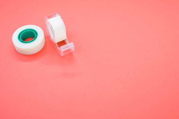 A top view closeup of a white duct tape and a tape dispenser isolated on a bright pink background - Fotó, kép