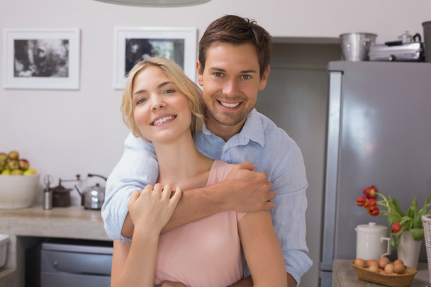 Man embracing woman from behind in kitchen - Foto, Bild