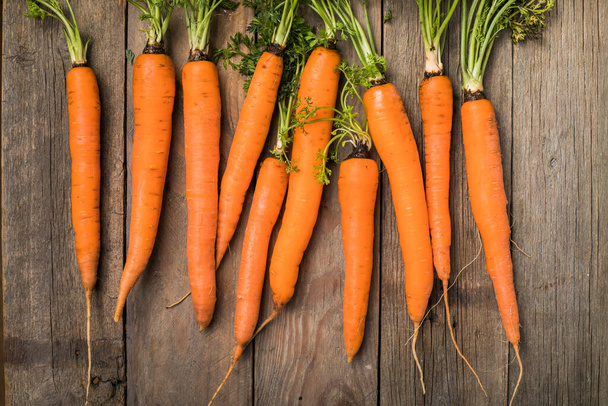 Frisches Karottenbüschel auf rustikalem Hintergrund. Gesunde vegane Gemüsekost. - Foto, Bild