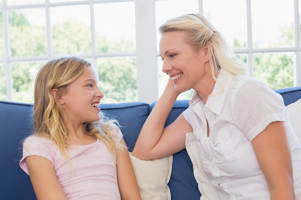 Happy mother and daughter sitting on sofa - Photo, image
