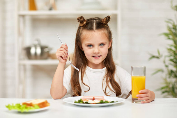 little child girl having breakfast - fried egg and orange juice - Foto, Bild