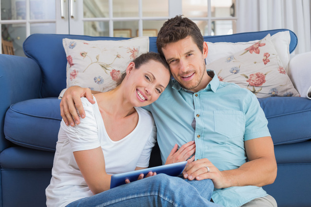 Happy couple using digital tablet in living room - Fotó, kép