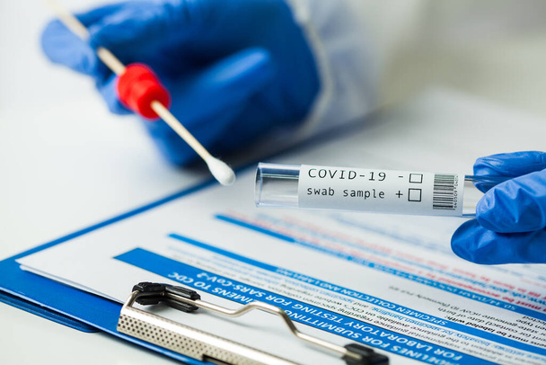 Trabalhador médico segurando Coronavirus COVID-19 NP OP kit de teste de amostra de swab, equipamento de coleta nasal, formulário de submissão CDC, transcrição reversa RT-PCR DNA procedimento de diagnóstico de ácido nucleico molecular  - Foto, Imagem