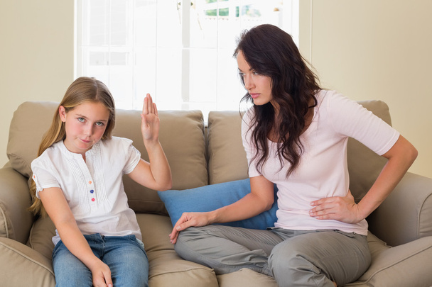 Girl showing stop gesture to mother on sofa - Foto, Bild