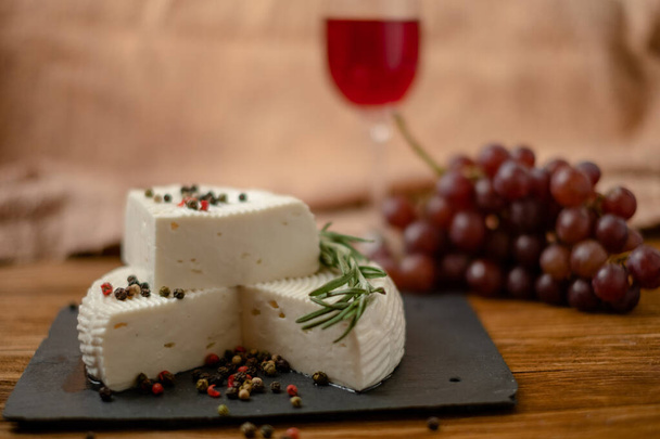 Goat cheese, grapes and wine lie on a wooden table. Cheese at home. - Foto, imagen