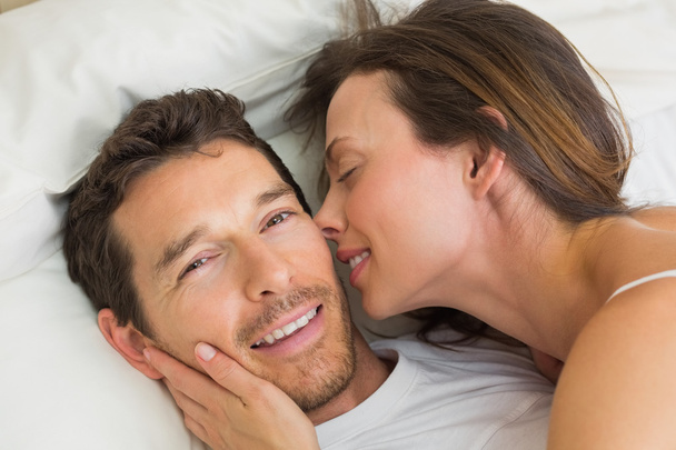Cheerful young couple lying together in bed - Foto, afbeelding