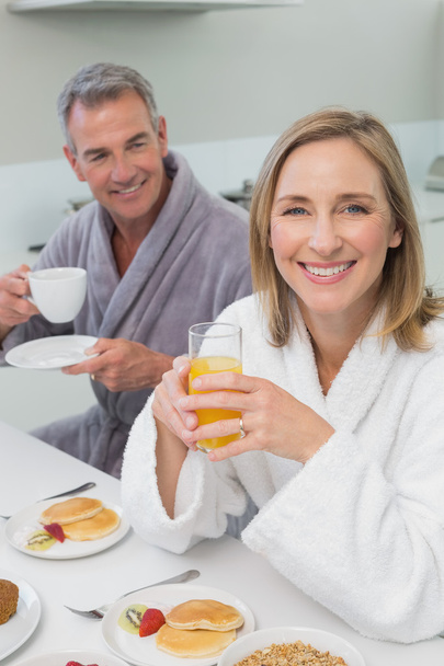 Smiling couple with orange juice and coffee in kitchen - Zdjęcie, obraz