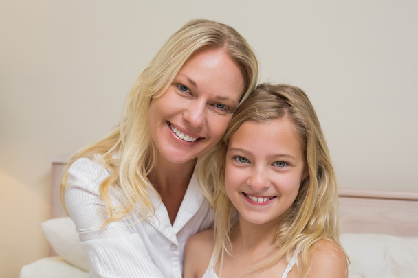 Mother and girl smiling in bedroom - Foto, afbeelding