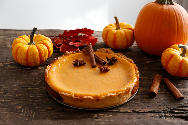 Traditional thanksgiving food on wooden table. Orange delicious homemade pumpkin pie with crust and decorative items. Thanksgiving table setting concept.Top view, close up, copy space, background. - 写真・画像