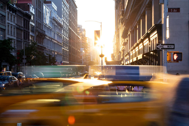ニューヨーク市23丁目と5番街の交差点を通る黄色のタクシー・ケーブルで、ミッドタウンの背景の建物の間に太陽の光が輝いています。 - 写真・画像