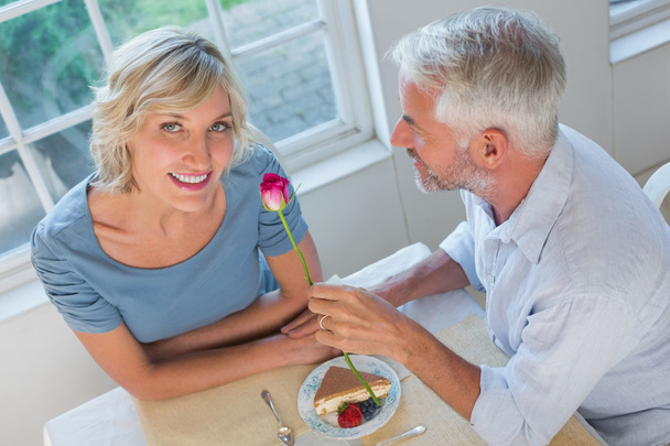 Mature man giving flower to a happy woman - Foto, afbeelding