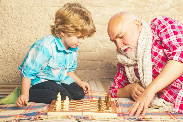 Mature man with little boy playing chess. Checkmate. Cute little boy playing chess. Childhood. Grandfather and grandson concept. Chess piece. - Photo, Image