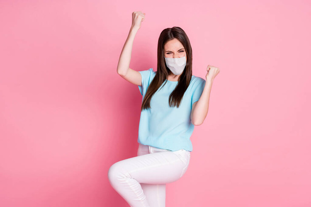 Photo of delighted girl raise fists wear white face mask isolated over pink color background - Fotografie, Obrázek