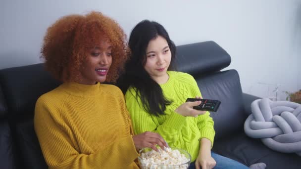 Monirotuinen ystävyys. Afican amerikkalainen musta ja aasialainen nainen syö popcornia ja katsoo elokuvia - Materiaali, video