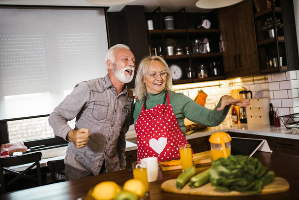 Старша пара насолоджується приготуванням свіжого соку разом на кухні
 - Фото, зображення