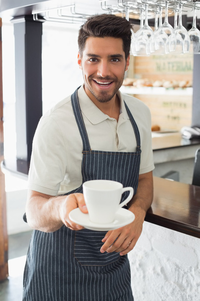 usměvavý číšník drží šálek kávy v kavárně - Fotografie, Obrázek