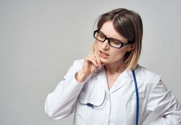 Arzt im Arztkittel mit Stethoskop um den Hals sieht verwirrt grauer Hintergrund aus - Foto, Bild